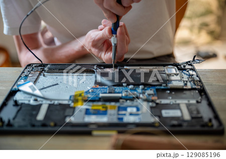 Man repairing laptop with tools on table, computer maintenance concept Man repairing laptop with tools on table, computer maintenance concept 129085196