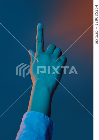 Hand pointing upward under dramatic blue and orange lighting Hand pointing upward under dramatic blue and orange lighting 129085254