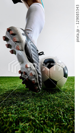 Close-up of cleated foot above soccer ball on field ready to kick Close-up of cleated foot above soccer ball on field ready to kick 129085343