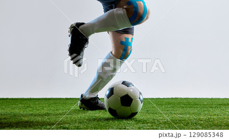 Soccer player with tape on knee getting ready to hit the ball on field Soccer player with tape on knee getting ready to hit the ball on field 129085348