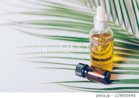 Bottle of essential oil is on a table next to a leaf Bottle of essential oil is on a table next to a leaf 129085648