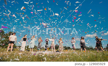 High school graduates joyfully celebrating with colorful confetti in a sunny outdoor setting 129085929