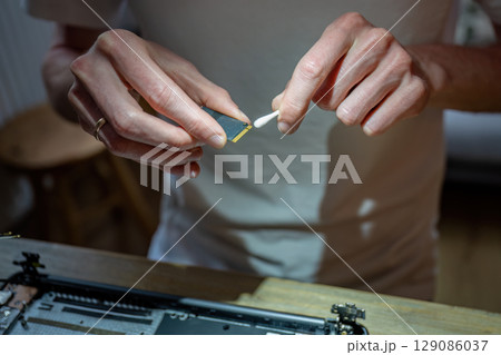 Close-up of man cleaning computer RAM module with cotton swab during laptop repair Close-up of man cleaning computer RAM module with cotton swab during laptop repair 129086037