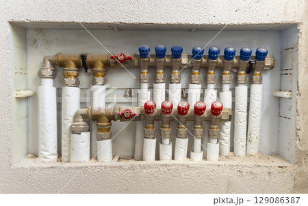 Pipes and valves for hot and cold water in heating and water supply system in boiler room closeup Pipes and valves for hot and cold water in heating and water supply system in boiler room closeup 129086387