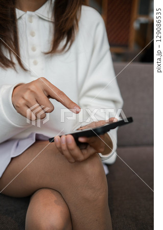 Close-up of a woman interacting with a smartphone, highlighting modern technology and casual lifestyle. 129086535