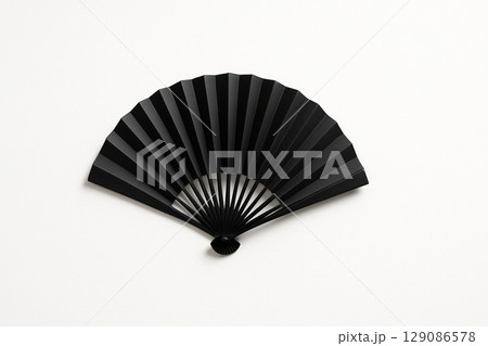 白い背景に置かれたシンプルな黒い扇子 129086578