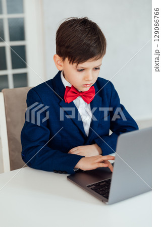 Schoolboy in Jacket Sitting At Table With Educational Laptop 129086766