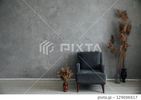 armchair and dried flowers in the interior of a gray room armchair and dried flowers in the interior of a gray room 129086817