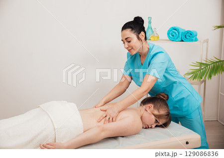 Massage therapist doing medical back and body massage to woman Massage therapist doing medical back and body massage to woman 129086836