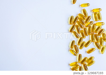 Pile of yellow gel capsules on white background Pile of yellow gel capsules on white background 129087193