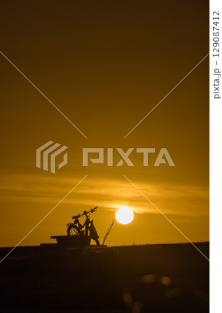 ニュージーランド ウェスト・コーストのホキティカ・ビーチに置かれた夕陽に照らされた自転車 ニュージーランド ウェスト・コーストのホキティカ・ビーチに置かれた夕陽に照らされた自転車 129087412