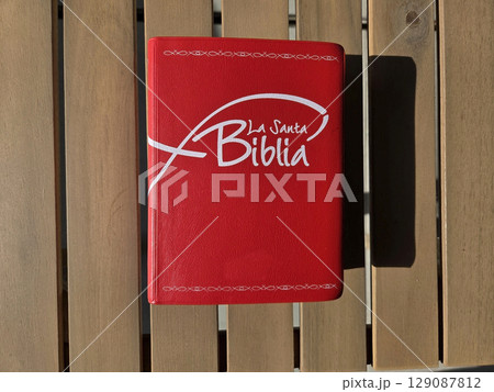 The holy bible with red cover on wooden table - spirituality and faith. Santa Biblia. First communion, baptism, wedding concept. Red book on a wooden background The holy bible with red cover on wooden table - spirituality and faith. Santa Biblia. First communion, baptism, wedding concept. Red book on a wooden background 129087812