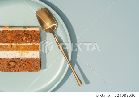 Bento carrot cake slice with orange and mango filling, displayed on a pastel plate with a golden serving spoon, showcasing layers of cake and cream, emphasizing the delightful cross-section Bento carrot cake slice with orange and mango filling, displayed on a pastel plate with a golden serving spoon, showcasing layers of cake and cream, emphasizing the delightful cross-section 129088930