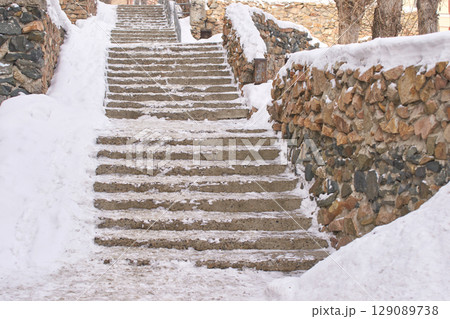 Snow covered stone staircase in winter with icy path and rocky walls in outdoor 129089738
