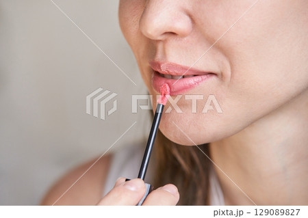 Young caucasian female applying pink lipstick closeup 129089827
