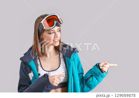 Young caucasian female in ski gear pointing with fingers in stylish winter 129089878