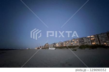 The serene Evening Beachfront is adorned with Glowing Lights, creating a Calm Atmosphere The serene Evening Beachfront is adorned with Glowing Lights, creating a Calm Atmosphere 129090352