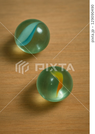Two Glass Marbles on Wooden Surface Two Glass Marbles on Wooden Surface 129090490