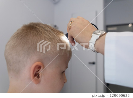 A pediatric dermatologist examining a young boys skin with a dermatoscope in a medical clinic. Skin check up for moles and birthmarks. 129090623