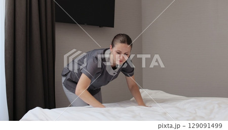 Chambermaid makes bed in hotel bedroom. Cleaning service in hotel rooms, hotel business. Chambermaid makes bed in hotel bedroom. Cleaning service in hotel rooms, hotel business. 129091499
