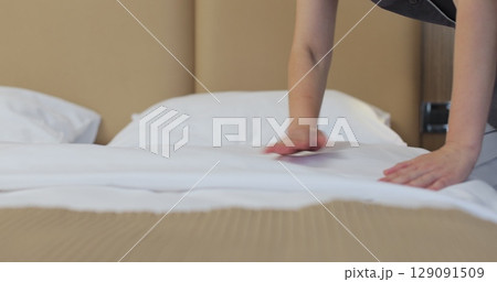 Female employee at the hotel beautifully makes the bed in the client's room. Hotel cleaning concept. Female employee at the hotel beautifully makes the bed in the client's room. Hotel cleaning concept. 129091509