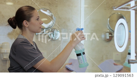 Young chambermaid cleaning mirror in hotel bathroom. Cleaning service concept. 129091563
