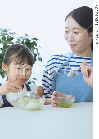かき氷を食べる娘とやさしく見守る母親の夏のひととき かき氷を食べる娘とやさしく見守る母親の夏のひととき 129091905
