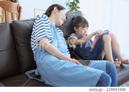 ソファで笑い合う母と娘の幸せなひととき ソファで笑い合う母と娘の幸せなひととき 129091906