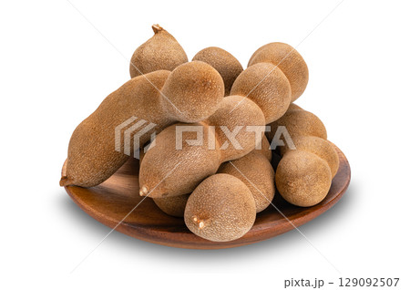 Pile of sweet Tamarind in wooden dish isolated on white background with clipping path. Pile of sweet Tamarind in wooden dish isolated on white background with clipping path. 129092507
