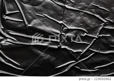 black crumpled and creased plastic poster texture background 129092662
