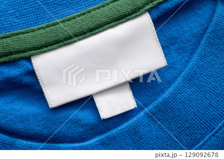 Blank white laundry care clothes label on blue shirt fabric texture background Blank white laundry care clothes label on blue shirt fabric texture background 129092678