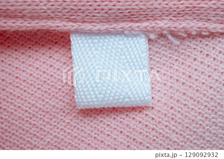 White blank laundry care clothes label on pink shirt fabric background 129092932