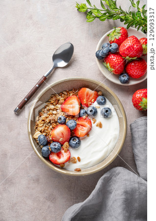 Natural greek yogurt with granola, blueberry and strawberry in a bowl on a light background Natural greek yogurt with granola, blueberry and strawberry in a bowl on a light background 129093317