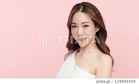 A beautiful young Asian woman with clean, fresh skin against a pink background. Skincare, facial treatment, cosmetology, beauty, and spa. An elegant portrait of an Asian woman. 129093504