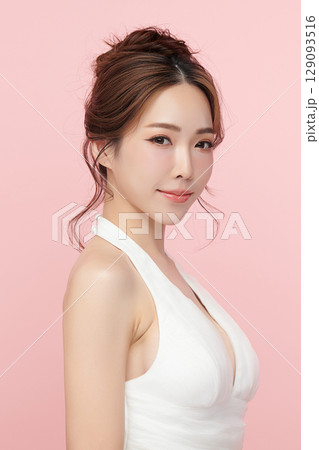 A beautiful young Asian woman with clean, fresh skin against a pink background. Skincare, facial treatment, cosmetology, beauty, and spa. An elegant portrait of an Asian woman. 129093516