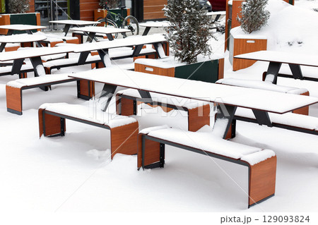 Tables and benches are covered in snow at an outdoor cafe Tables and benches are covered in snow at an outdoor cafe 129093824