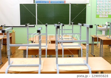 Empty Classroom with Chairs on Desks, Symbolizing the End of the School Year and New Beginnings Empty Classroom with Chairs on Desks, Symbolizing the End of the School Year and New Beginnings 129093828