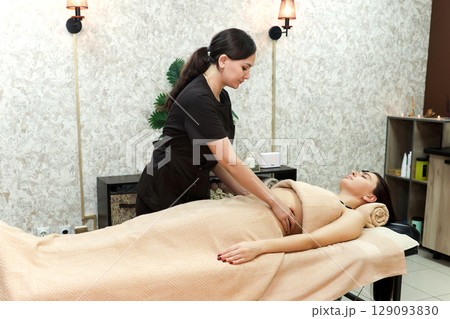 Gentle abdominal massage for a spa client, health and body care concept Gentle abdominal massage for a spa client, health and body care concept 129093830