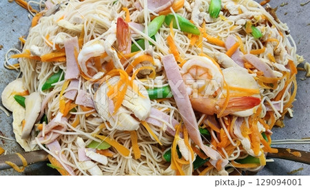 A close-up shot of stir-fried noodles with ham, shrimp and colorful vegetables 129094001