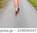 Legs in inline skates boots are moving on asphalt road 129094347