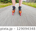 Legs in inline skates boots are moving on asphalt road 129094348