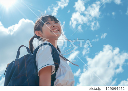 雲間からの日差しを浴びて笑う女子学生 129094452
