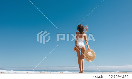 白い水着と帽子の女性の後ろ姿｜青空と海が広がる夏のビーチシーン 129094880