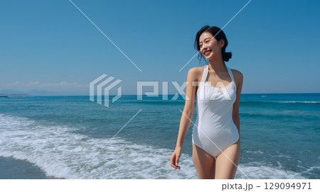 白い水着の女性と夏の海辺｜青空と波が広がる爽快なビーチシーン 129094971