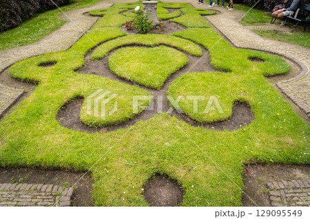 Figure made of green lawn grass in the park, free space. Green grass covered topiary, landscape design. Grass figure, topiary figure. 129095549