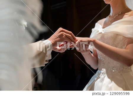 結婚式の指輪交換、新郎が新婦の指に指輪をはめる 結婚式の指輪交換、新郎が新婦の指に指輪をはめる 129095596