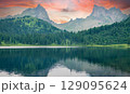 Forest lake at sunset with mountain peaks in the background 129095624