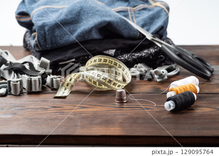 Metal thimble with sewing tools and clothing background. Metal thimble with sewing tools and clothing background. 129095764