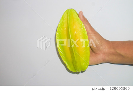 Asian Woman holding belimbing or star fruit in hand on white background. Tropical fruit Indonesia  129095869