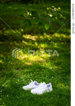 Pair of white sport shoes on grass field Pair of white sport shoes on grass field 129096034